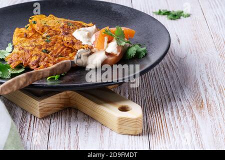 Sweet potato fritters with hummus, smoked salmon and pistachios on rural wooden table Stock Photo