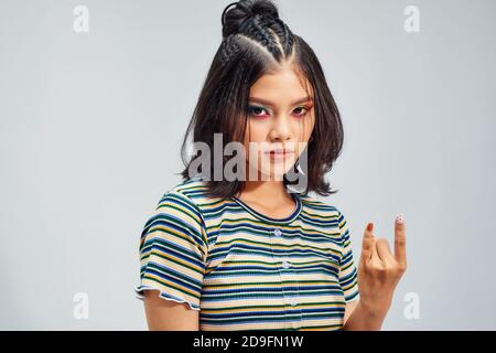 Crazy beautiful rock Girl. Punk is not dead. Attractive cool young woman making horn sign hand gesture. Stock Photo