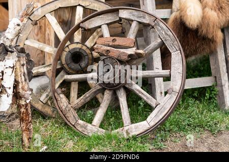 an old wooden cart wheel stands by the fence Stock Photo