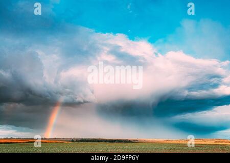 Dramatic Sky During Rain With Rainbow On Horizon Above Rural Landscape Field. Agricultural And Weather Forecast Concept. Countryside Meadow In Autumn Stock Photo