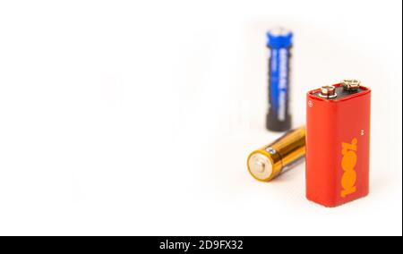 three different colors and sizes of batteries on a white background. Stock Photo