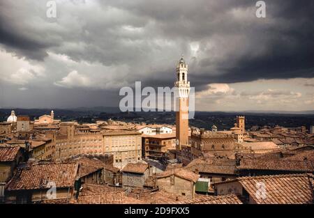 Siena, Piazza del Campo with the Torre del Mangia (Pubblico Palace tower) as storm clouds gather. Tuscany, Italy, Europe