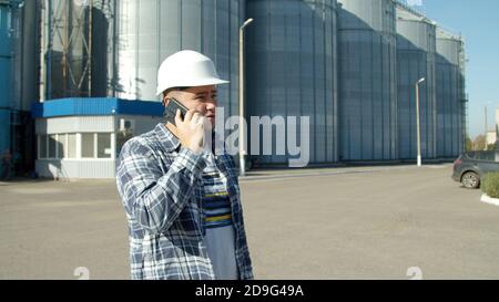 Engineer talking on phone near grain elevator Stock Photo