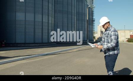 Professional engineer with blueprints inspecting agricultural silos Stock Photo