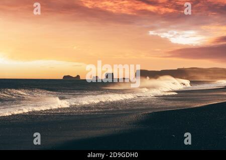 Incredible sunset view on stormy Atlantic ocean on Black Beach, Vik, Iceland. Big waves, orange sky and dark rocks. Landscape photography Stock Photo