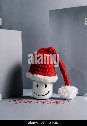 smiling doll with Santa Claus hat in front of grey walls Stock Photo