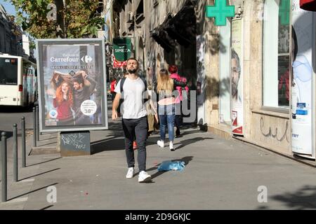 Downtown Bucharest, Romania. Young person walking by trash on the sidewalk. Stock Photo