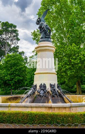 The Fallen Angel statue at El Retiro Park is framed suitably by a dark cloudy sky - Madrid, Spain Stock Photo