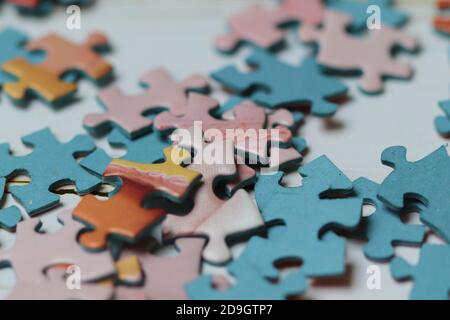 Closeup of colorful puzzle pieces placed on top of each other in a messy way on a white surface Stock Photo
