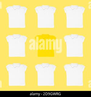 Yellow t-shirt among white ones on color background. Concept of uniqueness Stock Photo