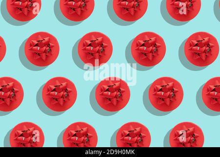 Pattern red gift box with decorative bow on blue surface top view flat lay. Holiday concept new year or Christmas gift box presents Xmas holiday. Stock Photo