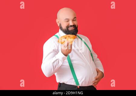 Overweight man with pizza on color background Stock Photo