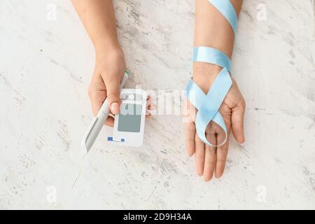 Female hands with awareness ribbon, glucometer and syringe on white background. Diabetes concept Stock Photo