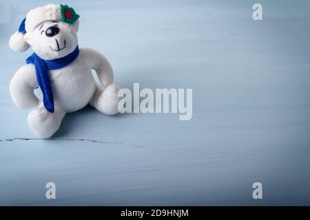 A sweet little soft bear toy figure with a Christmas hat on a white wooden background Stock Photo