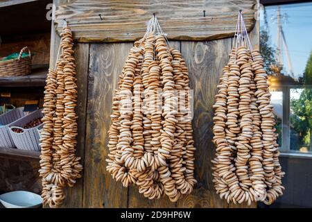 A lot of bagels on ropes hang on wooden wall in grocery Stock Photo