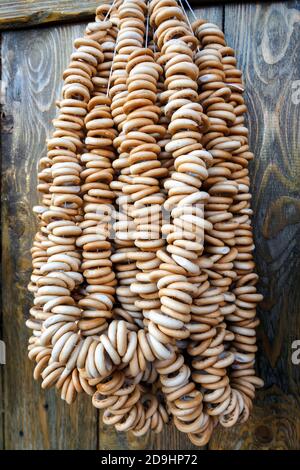 A lot of bagels on rope hang on wooden wall, vertical view. Stock Photo