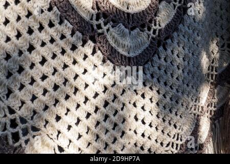 Close-up of knitted shawl wool of beige and brown color. Textured background, selective focus. Stock Photo