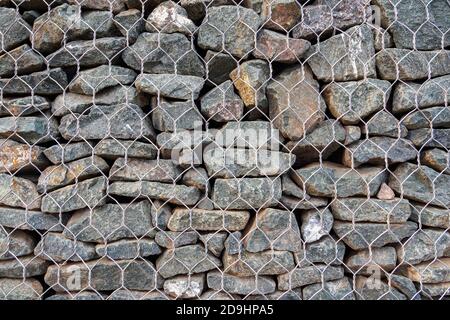 Mesh and stone fence, close-up of gabion for use in civil engineering, road building landscaping. Stock Photo