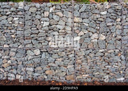 Mesh and stone fence, gabion for use in civil engineering, road building, military applications and landscaping. Stock Photo