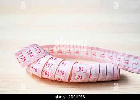 close up of measuring tape on a beige wooden background, selective focus, copy space Stock Photo
