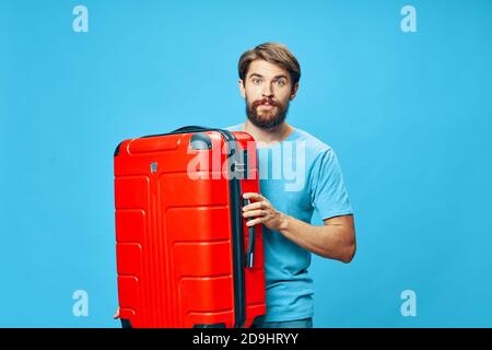 Traveler with a red suitcase blue t-shirt isolated background mustache on his face Stock Photo