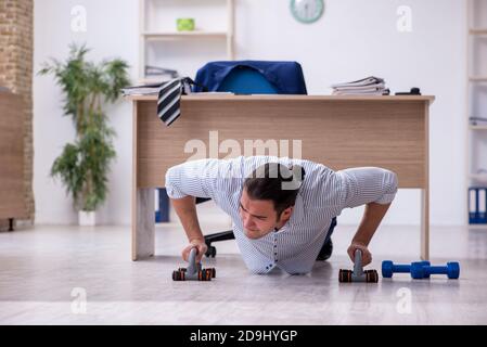 Handsome male employee doing exercises in the office Stock Photo