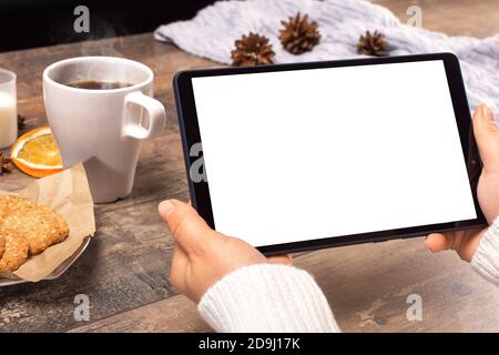 Mockup tablet pc. woman's hands holding black tablet pc with blank white screen horizontally while sitting in cafe. winter Christmas time Stock Photo