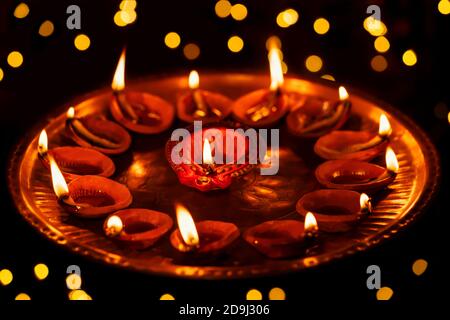 Clay diya oil lamps burning, lit or illuminated on Diwali night in dark bokeh background at home. Concept for Indian Hindu festival celebration. Stock Photo