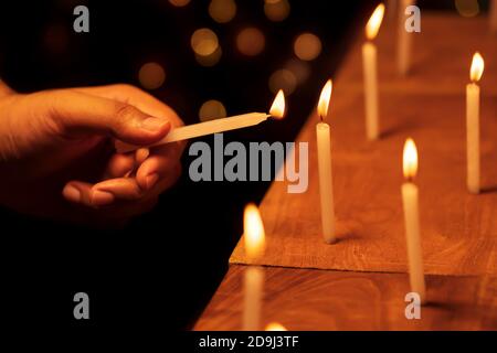 Male hand illuminating or lighting up the candles on Diwali night at temple, church. Stock background image for festive decoration, holiday, banner. Stock Photo