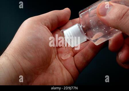 Protect from bacteria, personal hygiene and influenza protection concept with hands applying alcohol based hand sanitizer gel isolated on dark black b Stock Photo