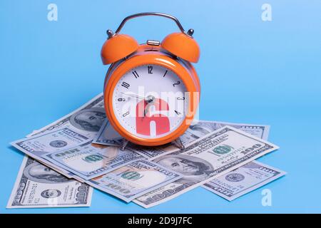 Time is money. Alarm clock and dollar banknotes. Business concept. Analog hours on a heap of paper dollars. Stock Photo
