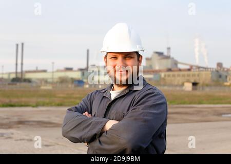 Portrait of engineer in helmet standing in construction site background. Stock Photo