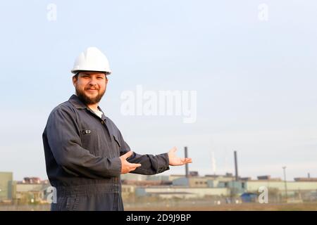 Portrait of male engineer in helmet standing in construction site background. Stock Photo