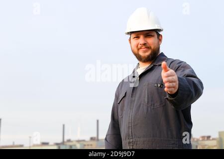 Portrait of caucasian foreman showing thumbs up standing in construction site background. Stock Photo