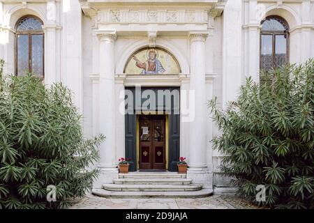 Orthodox church entrance with golden mosaics and trees Stock Photo