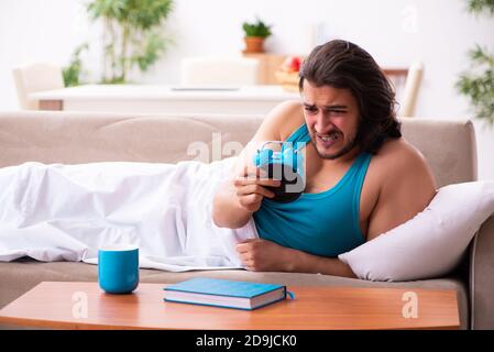 Young man lying on sofa in time management concept Stock Photo