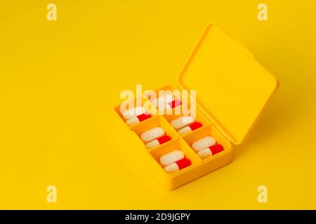 Yellow pillbox with pills on a yellow background Stock Photo