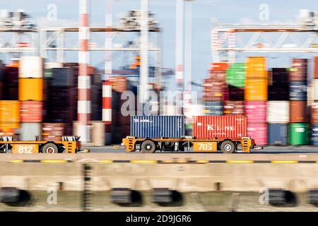 Panning shot of Automated guided vehicle carrying two containers on the quay of a Rotterdam port terminal Stock Photo