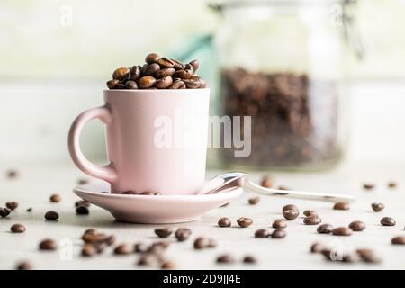 Roasted coffee beans in cup on white table. Stock Photo