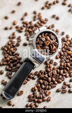 Roasted coffee beans in coffee filter holder on white table. Stock Photo