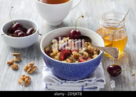 Healthy delicious vegan breakfast. Quinoa with fresh cherries, walnuts and honey on the wooden background, selective focus Stock Photo