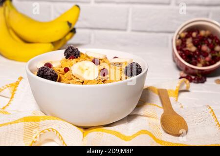 Dish with Corn Flakes, Banana, Berries and Wooden Spoon on white background, Healthy Breakfast Stock Photo