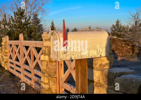 mailbox at the village wooden gate and stone fence on a winter morning Stock Photo