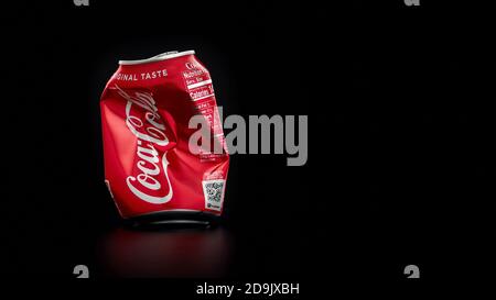Crumpled Coca Cola can on black background. Coca Cola drinks are produced and manufactured by The Coca-Cola Company, an American multinational Stock Photo