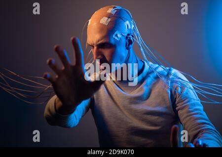 Man with a bald head with wires connected. Fear and anxiety. Examination of the brain, mind control. Stock Photo