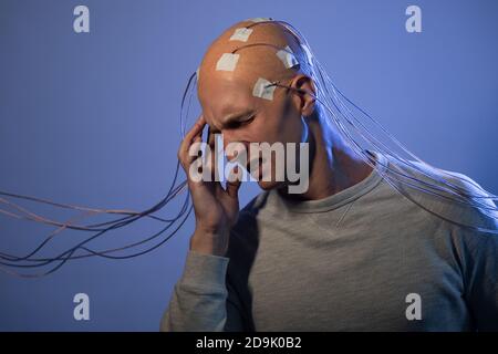 Man with a bald head with wires connected. Fear and anxiety. Examination of the brain, mind control. Stock Photo
