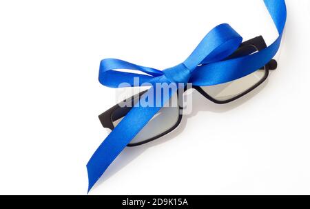Glasses with graduated glasses and black frame, classic plastic on white background and red gift ribbon Stock Photo