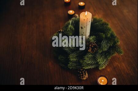 Advent wreath with burning candles on table. Christmas holiday decorations. Stock Photo