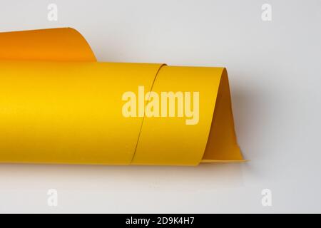Isolated rolled yellow textured art paper on white background Stock Photo