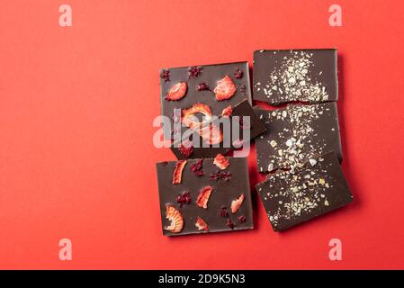 Handmade chocolate bars with berries on a red background. View from above. Stock Photo